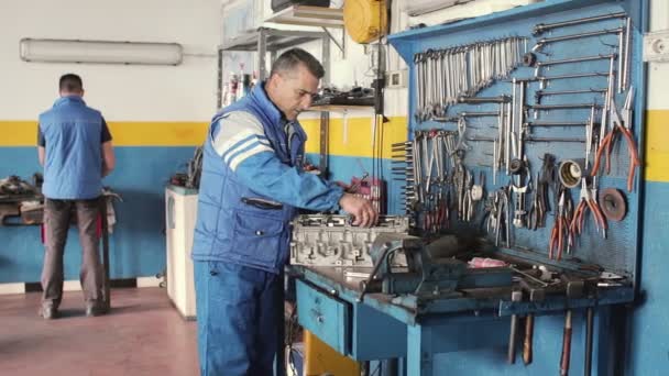 Mecánico de automóviles reparando una parte de un motor de coche — Vídeos de Stock