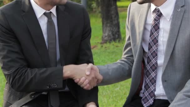 Два счастливых бизнесмена заключают сделку, пожимая друг другу руки. — стоковое видео