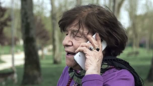 Anciana enojada hablando de un teléfono móvil: llamada telefónica problemática, ira — Vídeo de stock