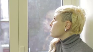 Genç düşünceli bir kadın pencereden dışarı bakar ve erkek arkadaşıyla tartıştığını düşünür.