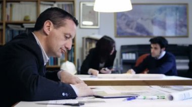 arka planda meslektaşları ile çalışan mimar: takım çalışması