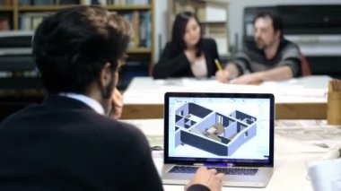 erkek mimar arka planda meslektaşları ile CAD yazılımı kullanarak