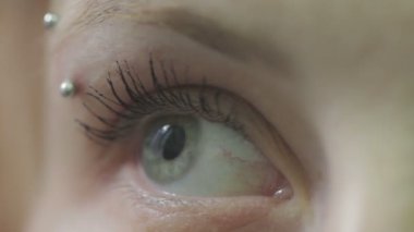 Kameraya bakan genç bir kadının mavi gözünün yakın çekimi.