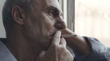 depresif adam pencerenin yakınındaki bulutlu bir günde Sigara
