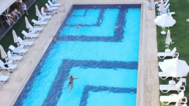 insanlar bir otelin havuzunda yüzüyor