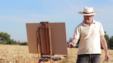 güzel bir manzara, tuval ortasında bir buğday alan ressam boyalar