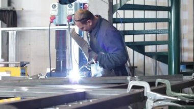 Metal işçisi fabrikada kaynak yapıyor.