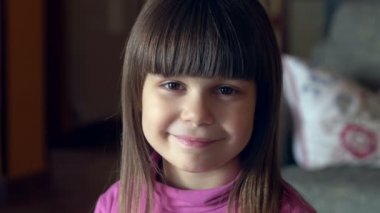 Küçük kız yakın plan portresi: Kameraya bakıyor ve gülümsüyor