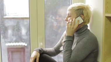 Genç üzgün bir kadın telefonu kullanıyor ve bir arkadaşını arıyor.