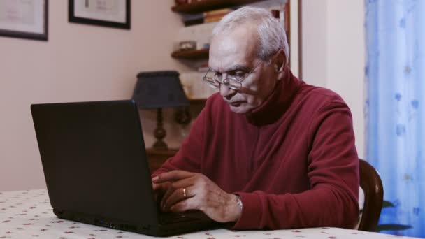 Homem velho que trabalha com computador portátil em casa — Vídeo de Stock