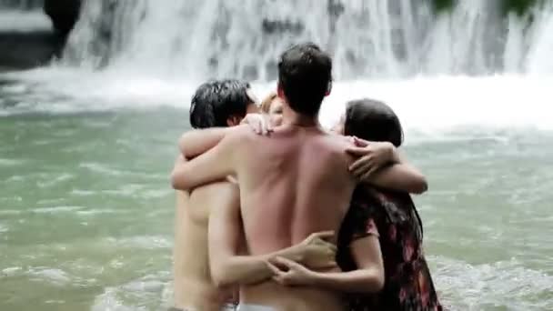 Dívky chlapců se bavit ve vodopádu. objímání a hrát si s vodou — Stock video
