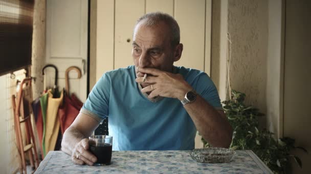 Velho está sentado sozinho bebendo vinho e fumando cigarro: solidão — Vídeo de Stock