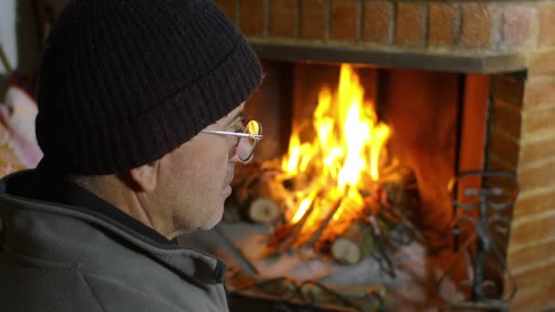 Hombre sentado cerca de la chimenea — Vídeos de Stock