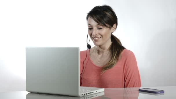 Mujer que trabaja con auriculares y computadora en un centro de atención al cliente — Vídeos de Stock