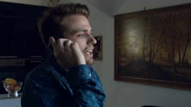 Jonge man met boze oproep op de mobiele telefoon: smartphone, interieur, home, 4k — Stockvideo