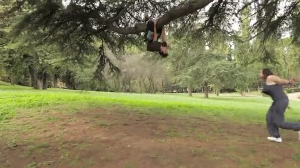 Женщина бежит к своему парню и целует его, мужчина на дереве вверх ногами — стоковое видео