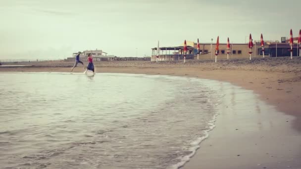 Due amanti inseguono (rincorrono) e si baciano in mare - spiaggia - amore - tramonto — Video Stock