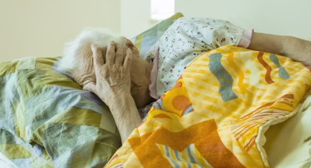 Uma mulher velha acorda de manhã, despertando uma mulher idosa, cama — Vídeo de Stock