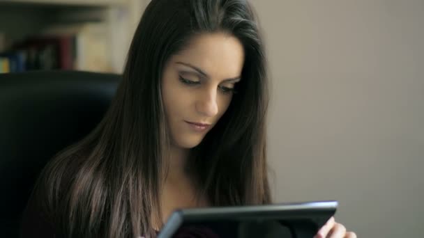 Молода жінка використовує планшет: офіс, вільний час, вікно, розслабляється, посміхається — стокове відео