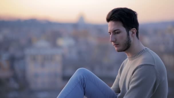 Young man sitting, looks upset. Man in front of the landscape — Stock video