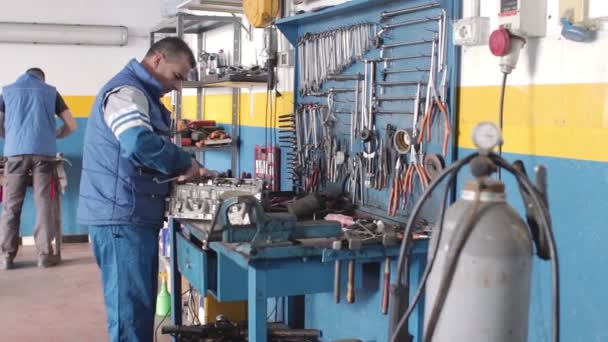 Auto mechanic repairing a part of a car engine — Stock Video