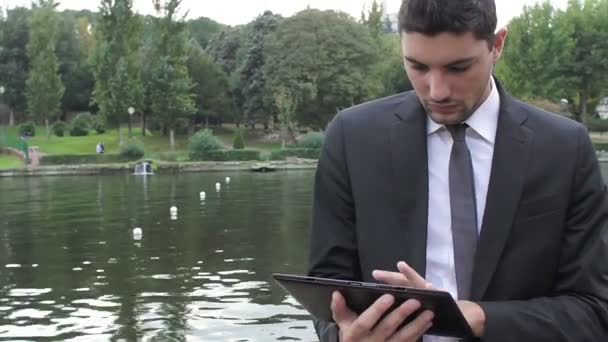 Homem de negócios usando tablet digital no parque — Vídeo de Stock