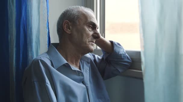 Старий депресивний чоловік у вікні: смуток, самотність, депресія — стокове відео
