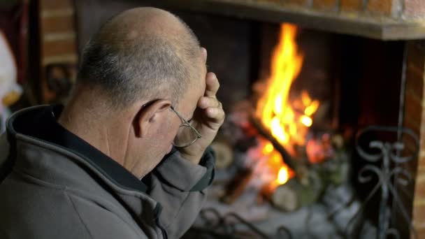 Σκεπτικός ο άνθρωπος που κάθεται δίπλα στο τζάκι — Αρχείο Βίντεο