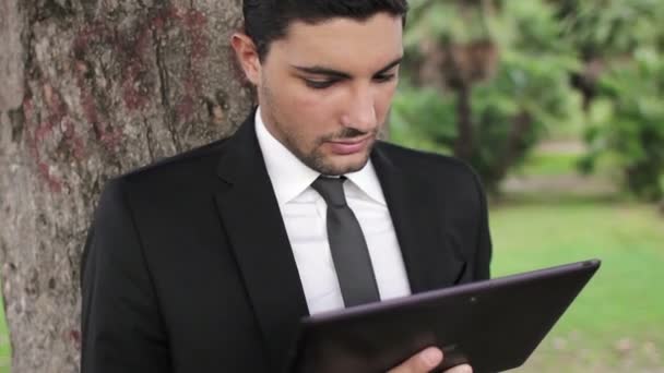 Jovem de negócios feliz usando tablet PC fora em um parque — Vídeo de Stock