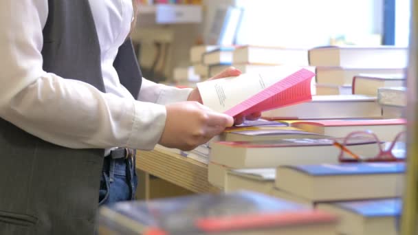 Jonge vrouw zoekt een boek in een boekwinkel — Stockvideo