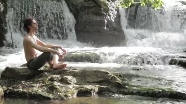 Young boy in meditation near the river — Stock Video