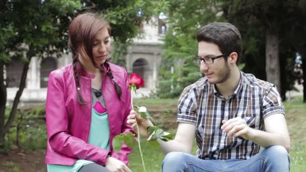 Um homem tímido dá uma rosa vermelha a uma bela mulher - amor - amor - amor - amor - beijo — Vídeo de Stock