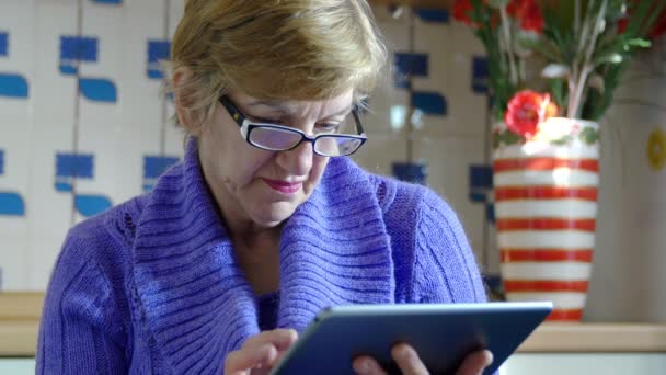 Donna elederly navigare su internet con il suo computer tablet: casalinga, cucina — Video Stock