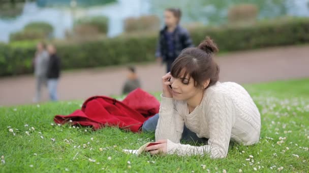 Hermosa joven está escribiendo un diario al aire libre en el parque: hierba, mentira , — Vídeos de Stock