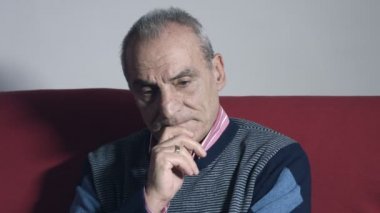 dalgın yaşlı adam tek başına evde oturan kırmızı kanepede