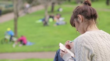 sevimli kız açık havada parkta oturan bir günlük yazma:
