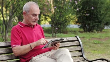 dinlenme ve park masasında onun tablet kullanarak emekli kıdemli adamı