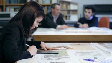 kadın mimar arka planda meslektaşları ile çalışma