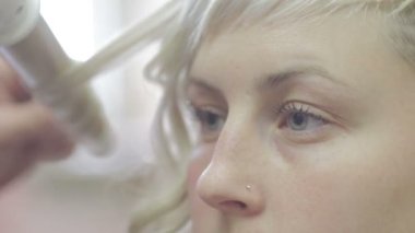 Bir kuaför müşteriye saç maşası kullanır.