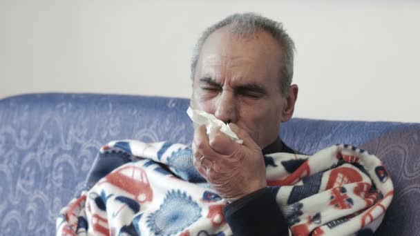 Velho doente com febre e frio: sentado no sofá com cobertor — Vídeo de Stock