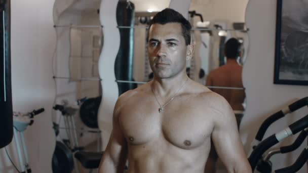 Hombre adulto en topless utiliza un ejercicio de peso en un gimnasio en casa para mantenerse en forma y stren — Vídeos de Stock