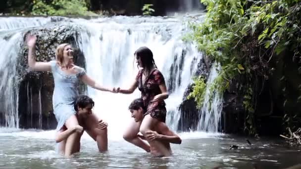 Meninos e meninas estão se divertindo em um rio, lutando e salpicando com água — Vídeo de Stock