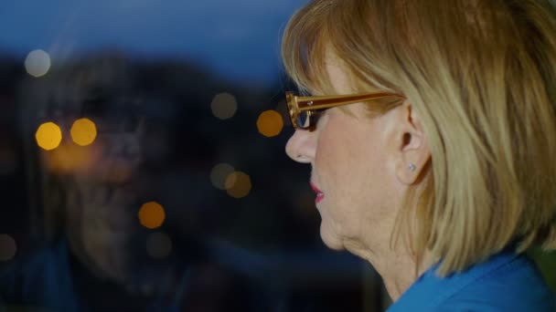 Mujer triste mirando las luces de la ciudad nocturna fuera de su casa — Vídeo de stock