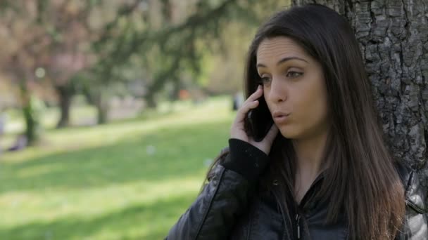 Ładna dziewczyna jest posiadanie zadzwonić w parku: smartphone: komórka, telefon komórkowy, odkryty — Wideo stockowe