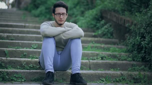 Lonely boy on staircase thinking about some problem: sad, upset, troubled — Stockvideo