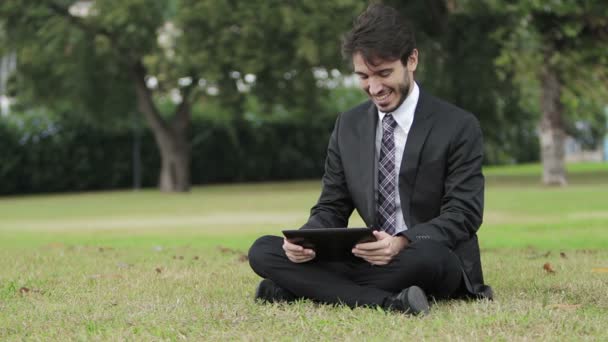 Joven hombre de negocios en el parque trabajando con la tableta — Vídeo de stock