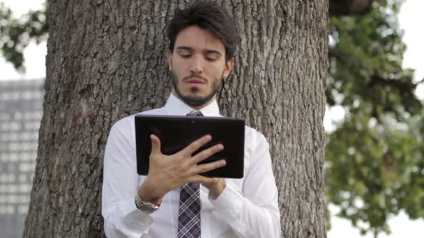 Άνθρωπος των επιχειρήσεων χρησιμοποιεί ψηφιακή δισκίο στο πάρκο — Αρχείο Βίντεο