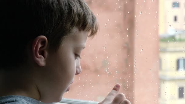 Ребенок пишет с пальцем на окне в дождливый день — стоковое видео