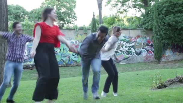 Група друзів веселяться в парку році радісні - стрибок - обійняти - запустити — стокове відео
