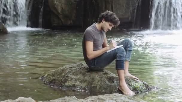 Um homem tomando notas sobre a natureza — Vídeo de Stock